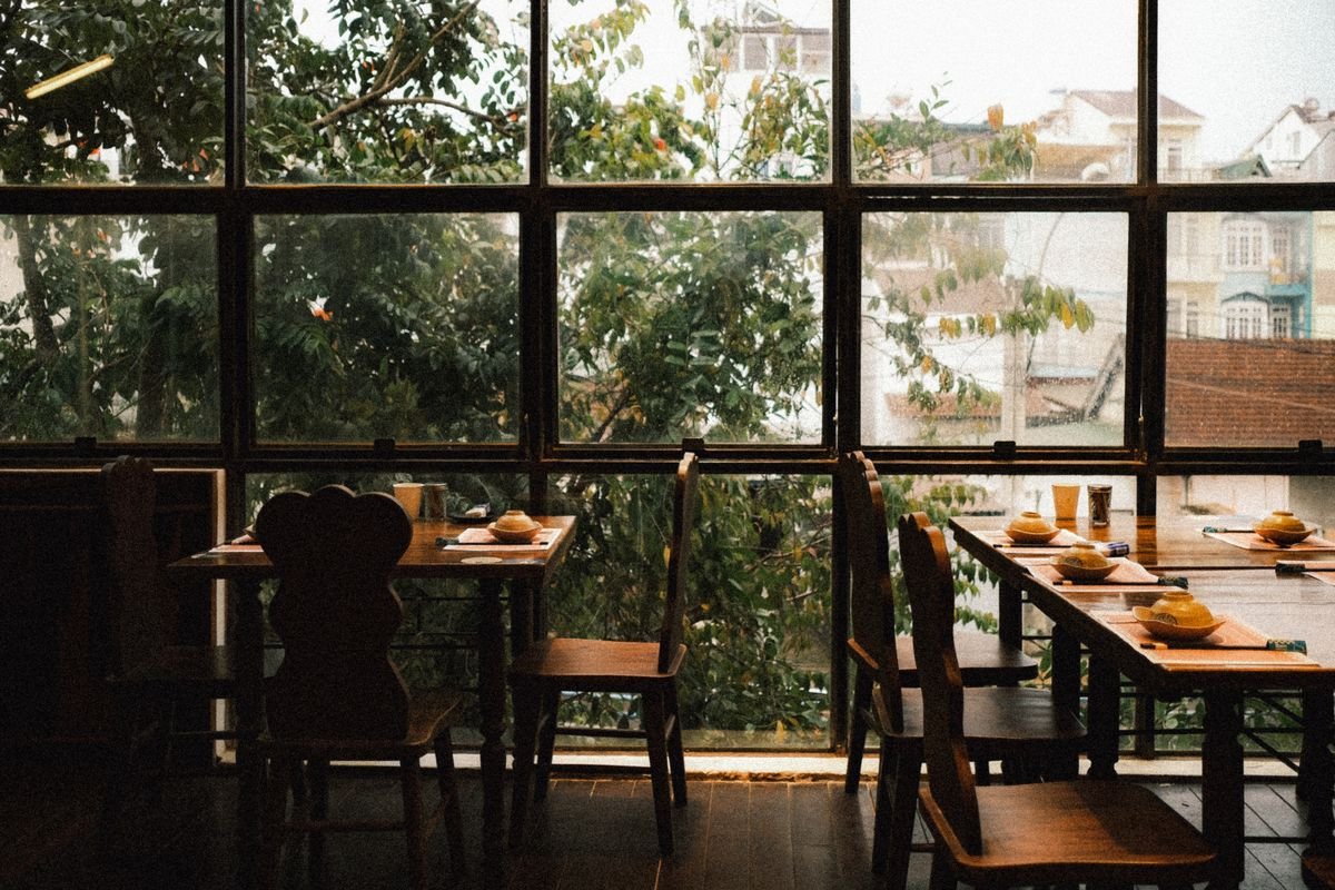 Sunlit restaurant with wood furniture and greenery