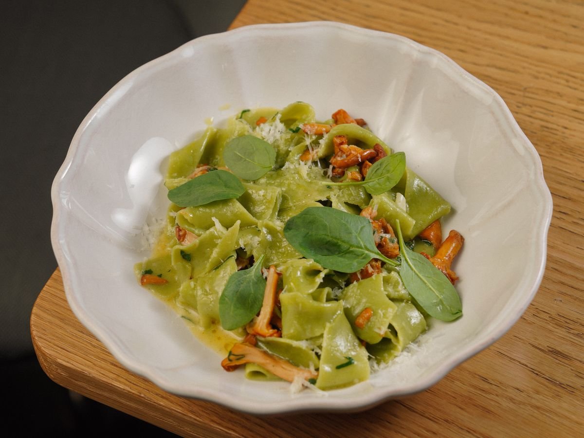 Spinach pasta with chanterelle mushrooms in a white bowl