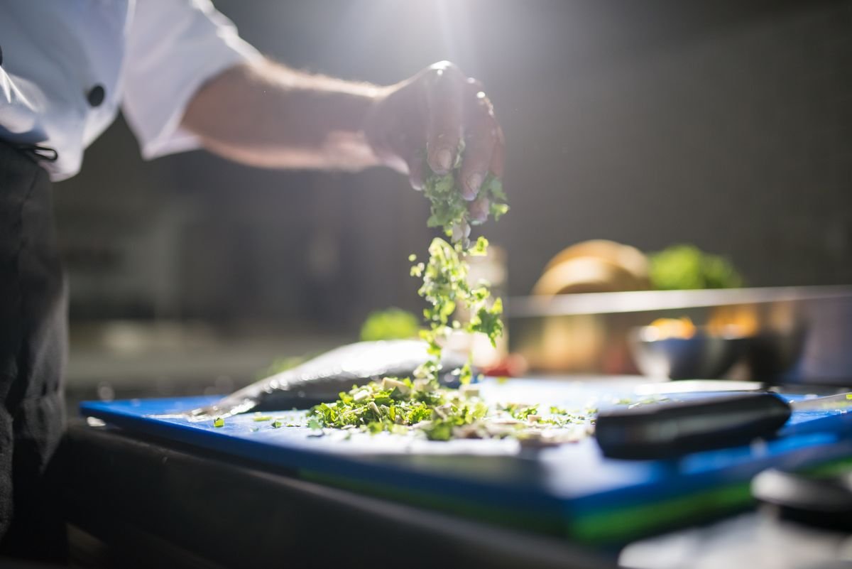 A cook chopping fresh green vegetables
