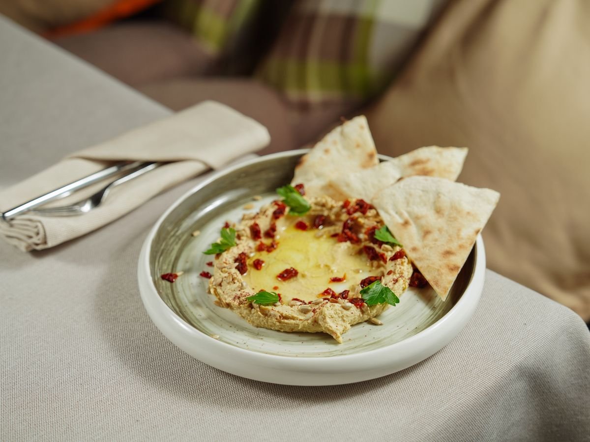 Hummus garnished with herbs and served with pita